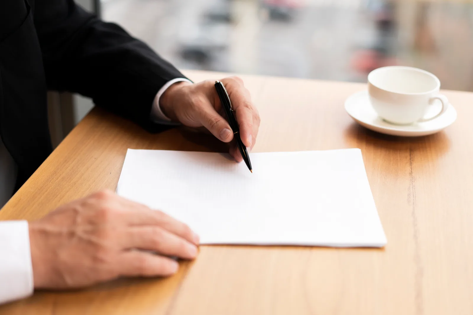 Hand holding a pen paused over the fine print of a service contract before signing