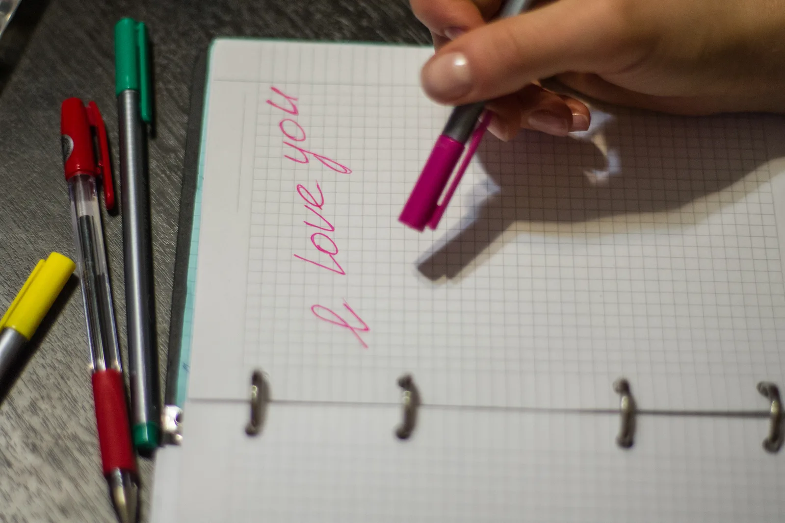 Hand filling in a paper monthly planner grid with short post topics in pen