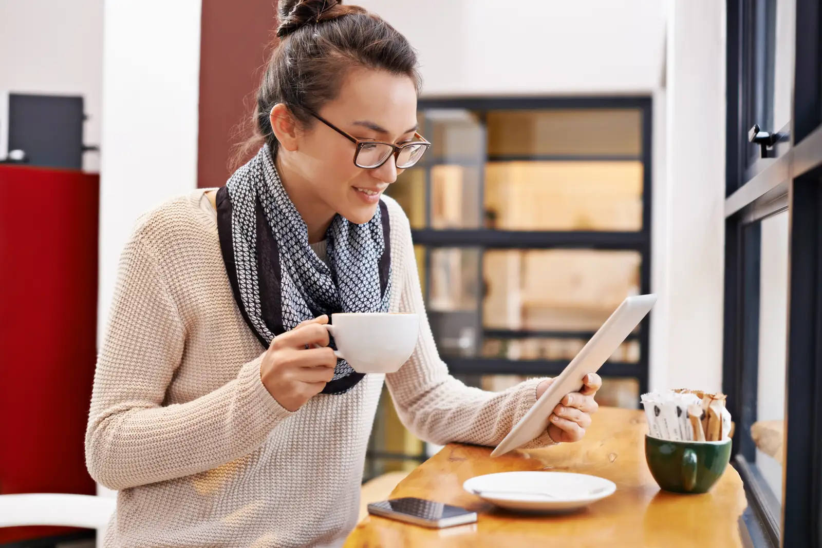 Owner reading an agency's pricing page on a laptop with a notepad and coffee beside it