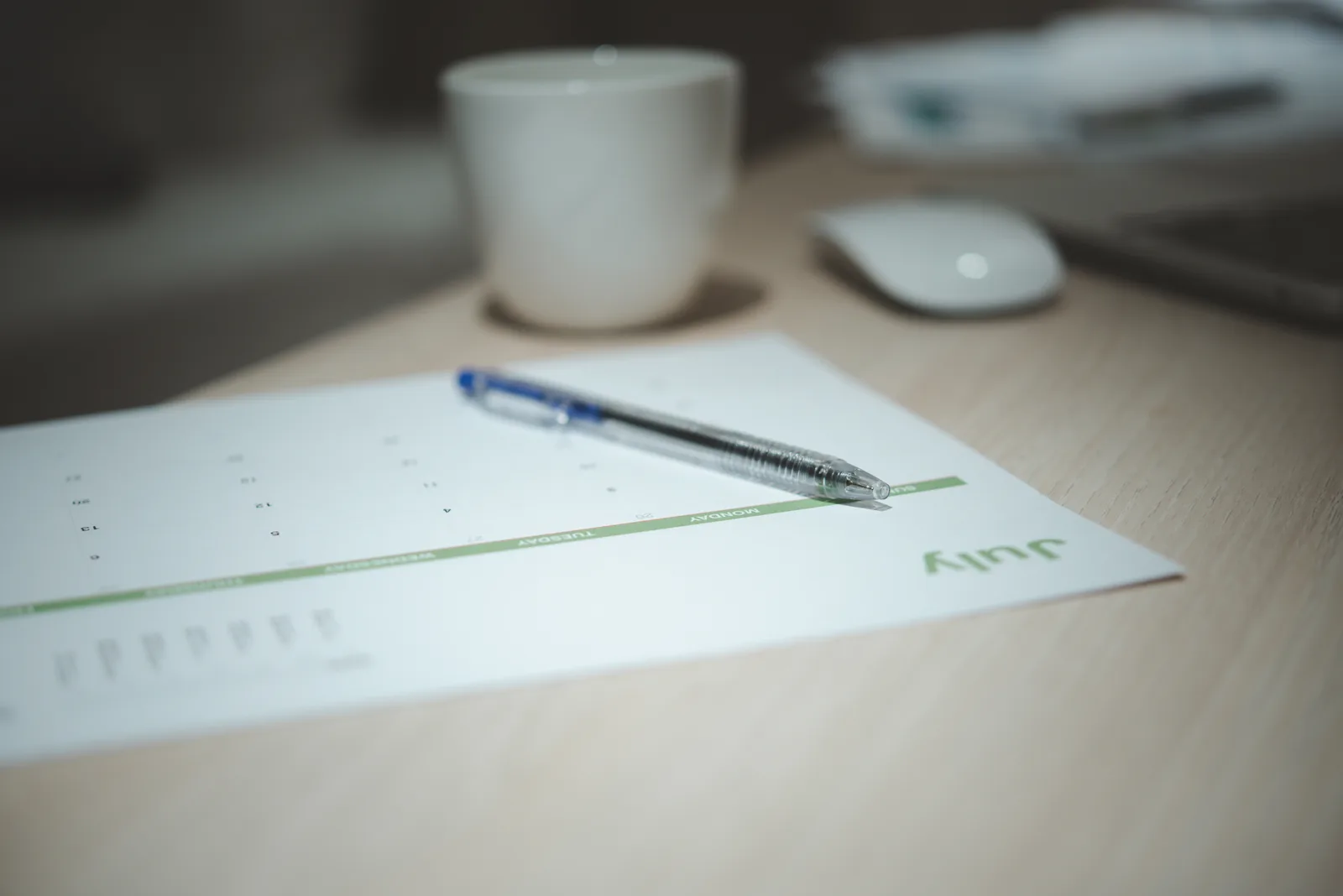 Printed monthly invoice next to an hourly timesheet on a desk, with a pen resting on top