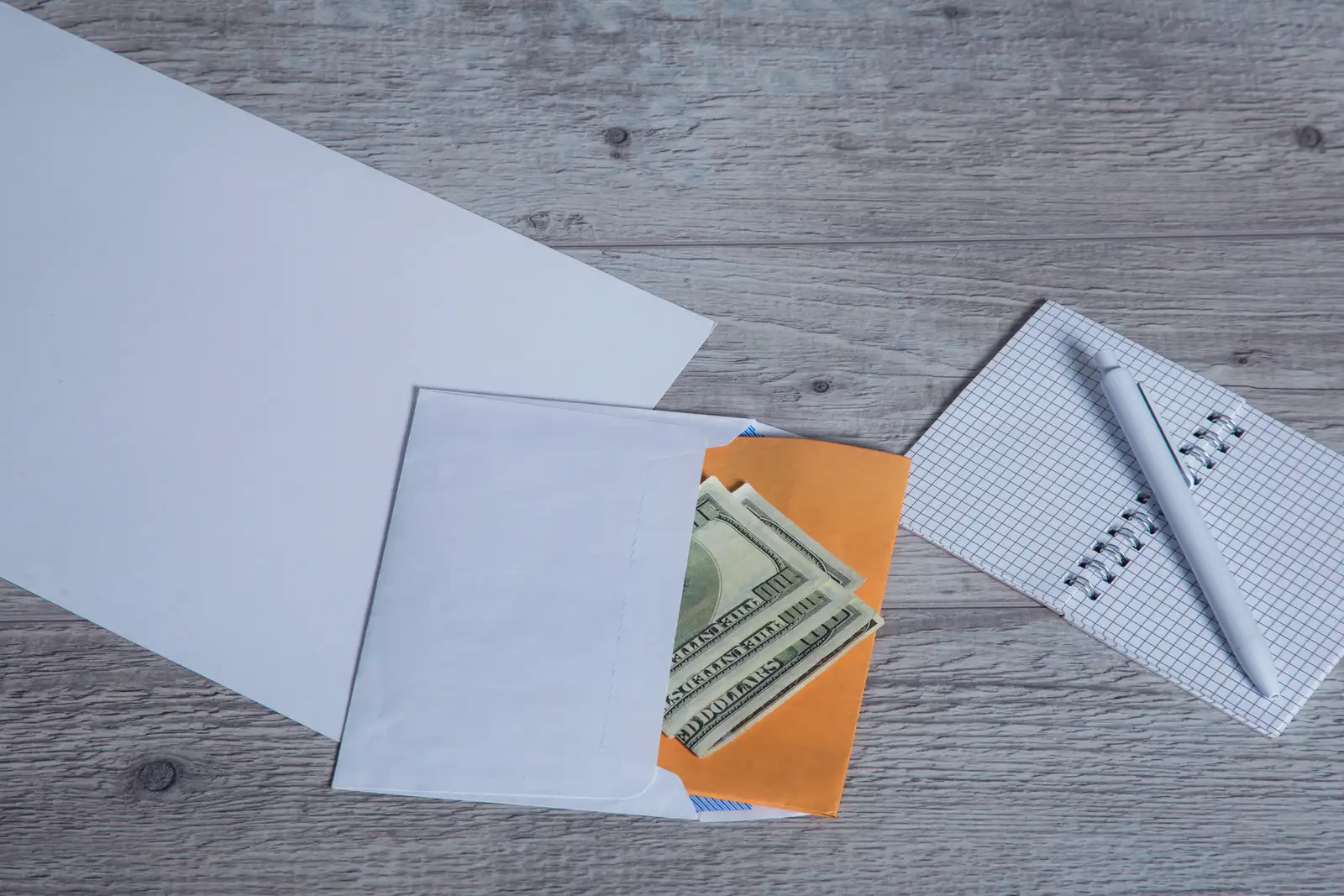 Two separate stacks of cash on a wooden table, one set aside for ads and one for fees