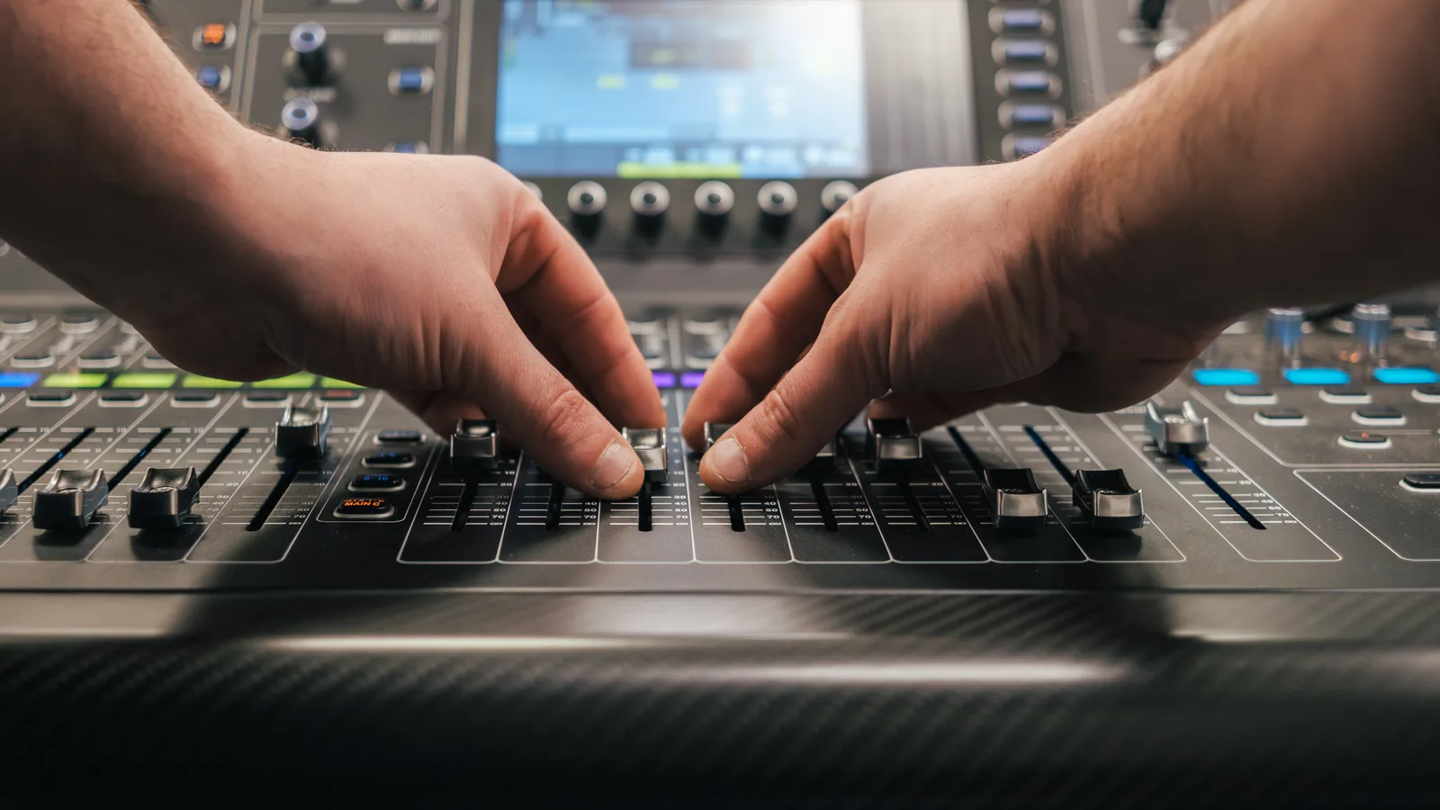 Engineer's hands working the faders of a digital mixing console — one operator running many channels, the way Claude runs GoHighLevel operations