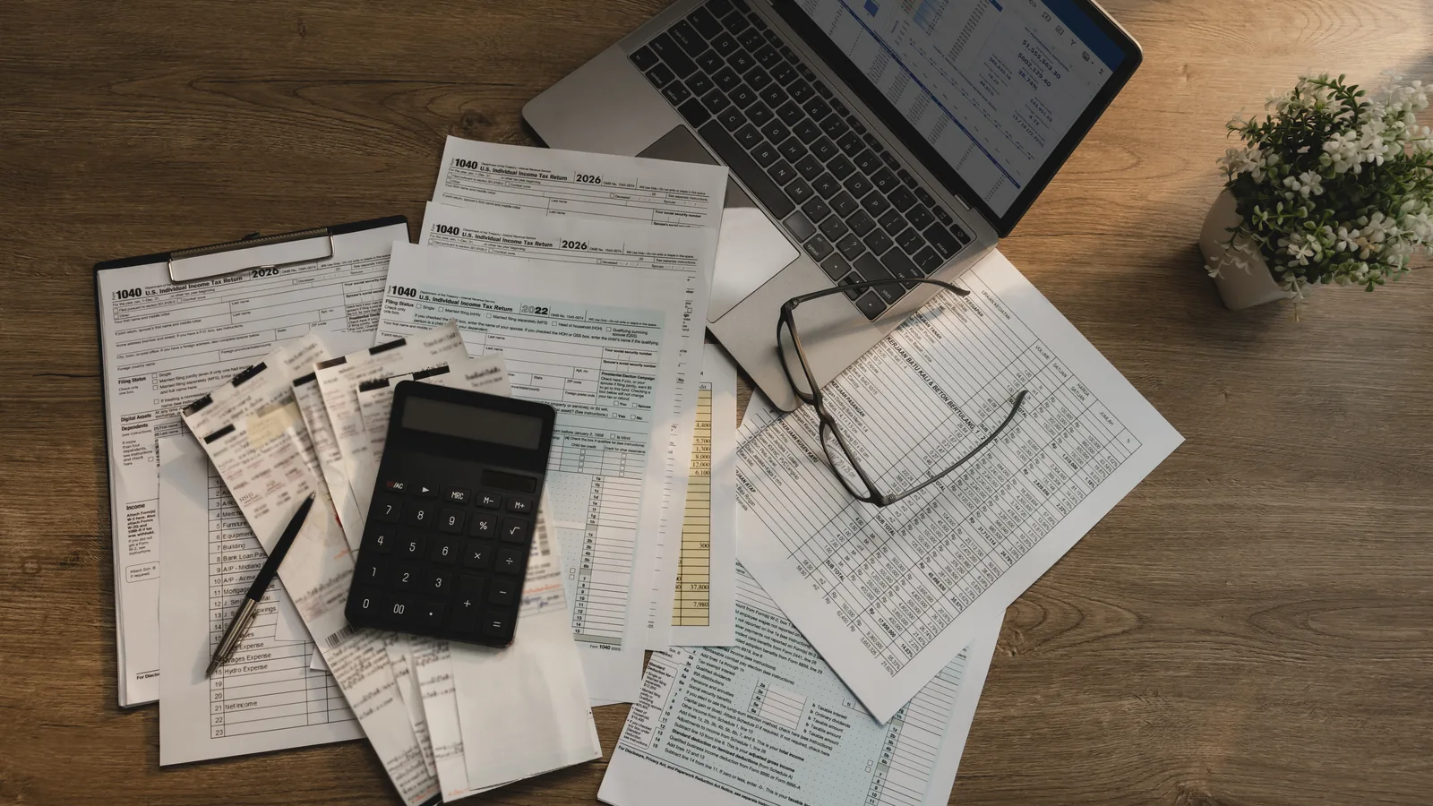 Desk with calculator, receipts, and financial spreadsheets on a laptop, representing an itemized GoHighLevel cost breakdown
