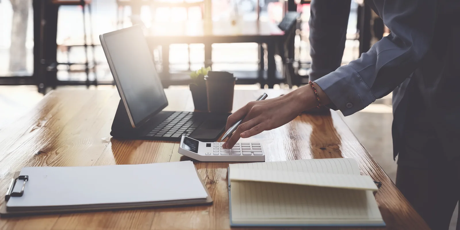 A business owner works through registration paperwork with a calculator and laptop on the desk