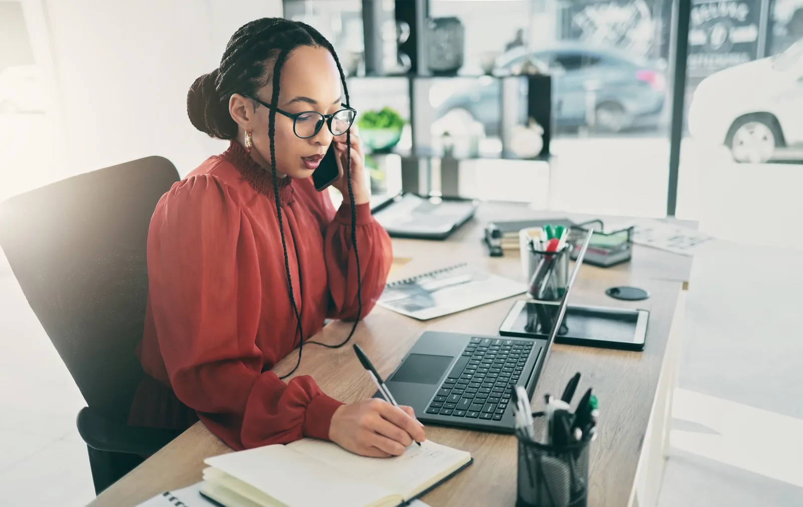 An operator on a call writes notes at her desk beside the laptop, deciding whether a client turns the AI on