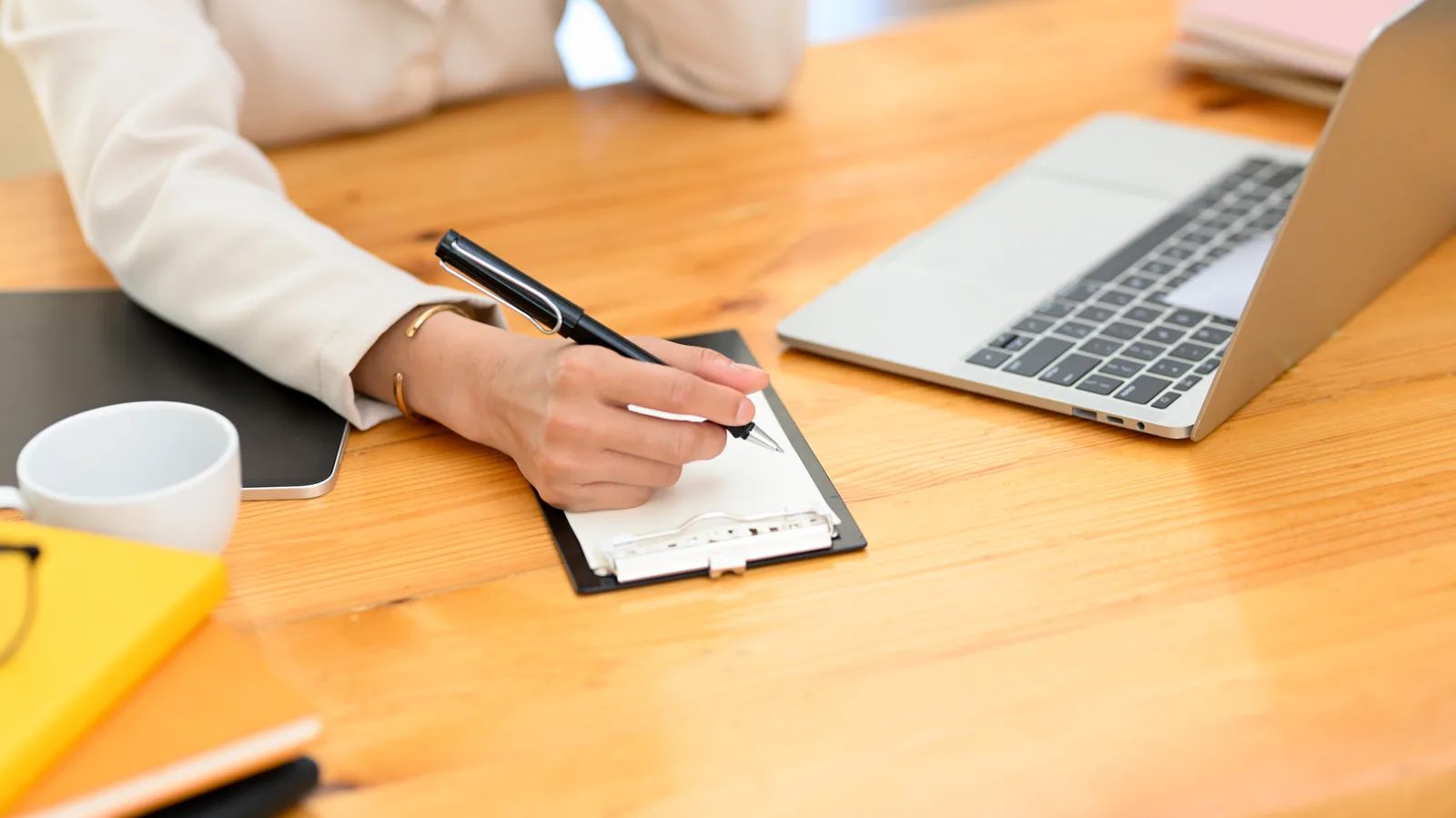 A hand ticks items on a clipboard beside an open laptop, working through the day-one steps
