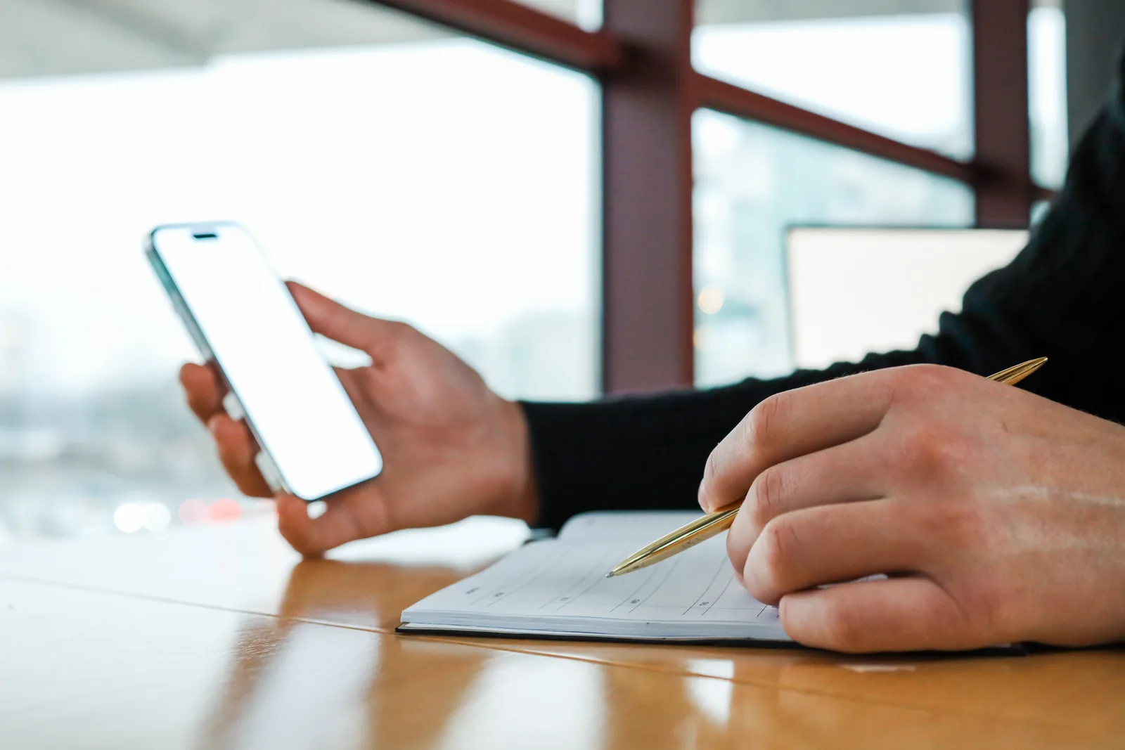 A hand writes in a planner with a gold pen beside a phone, the consent record on paper