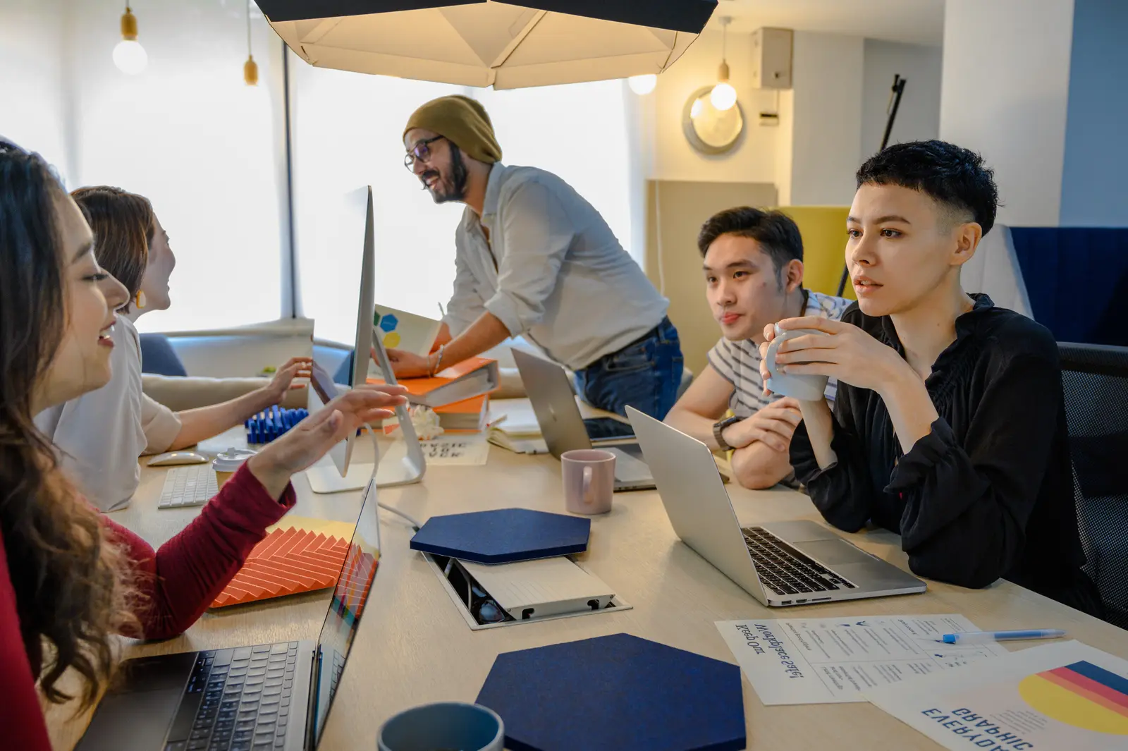A small agency team around a table of laptops and monitors, mid-project