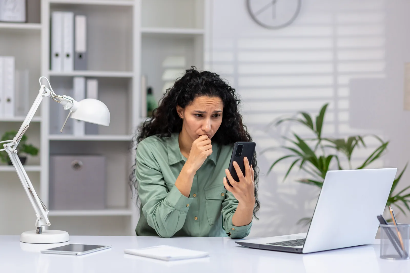 A worried business owner at her desk reads her phone, the texts that never reached the customer
