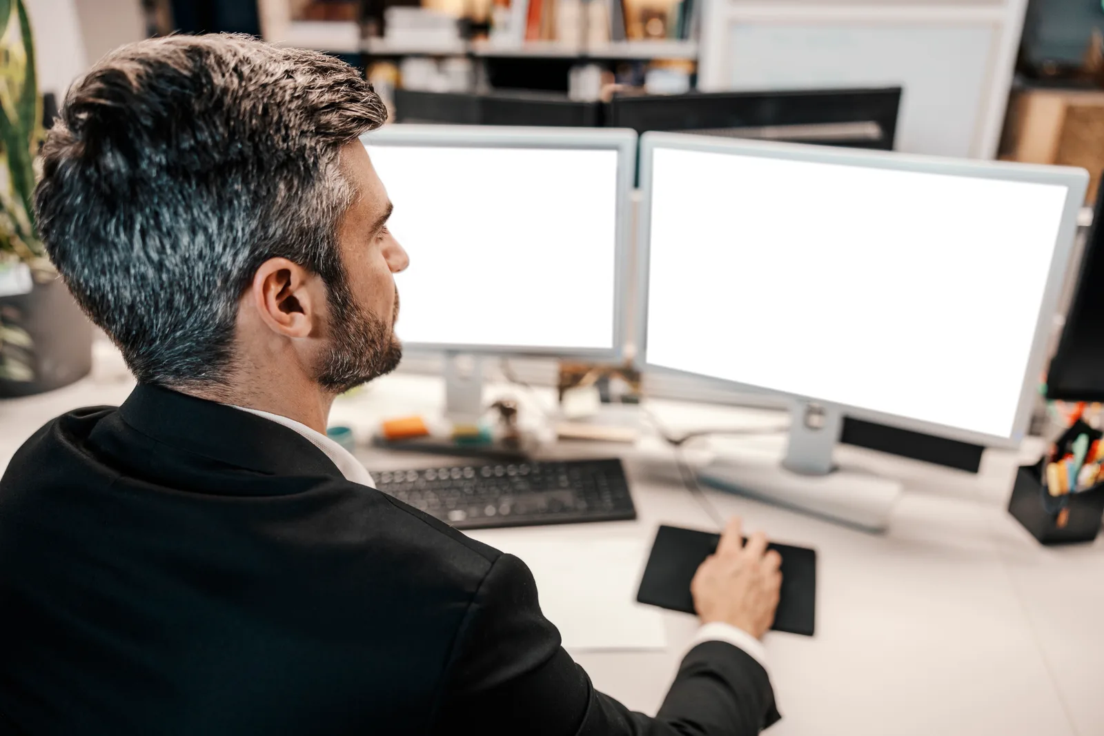 Seen from behind, an operator sits at a two-monitor desk, the side-by-side setup a snapshot check needs