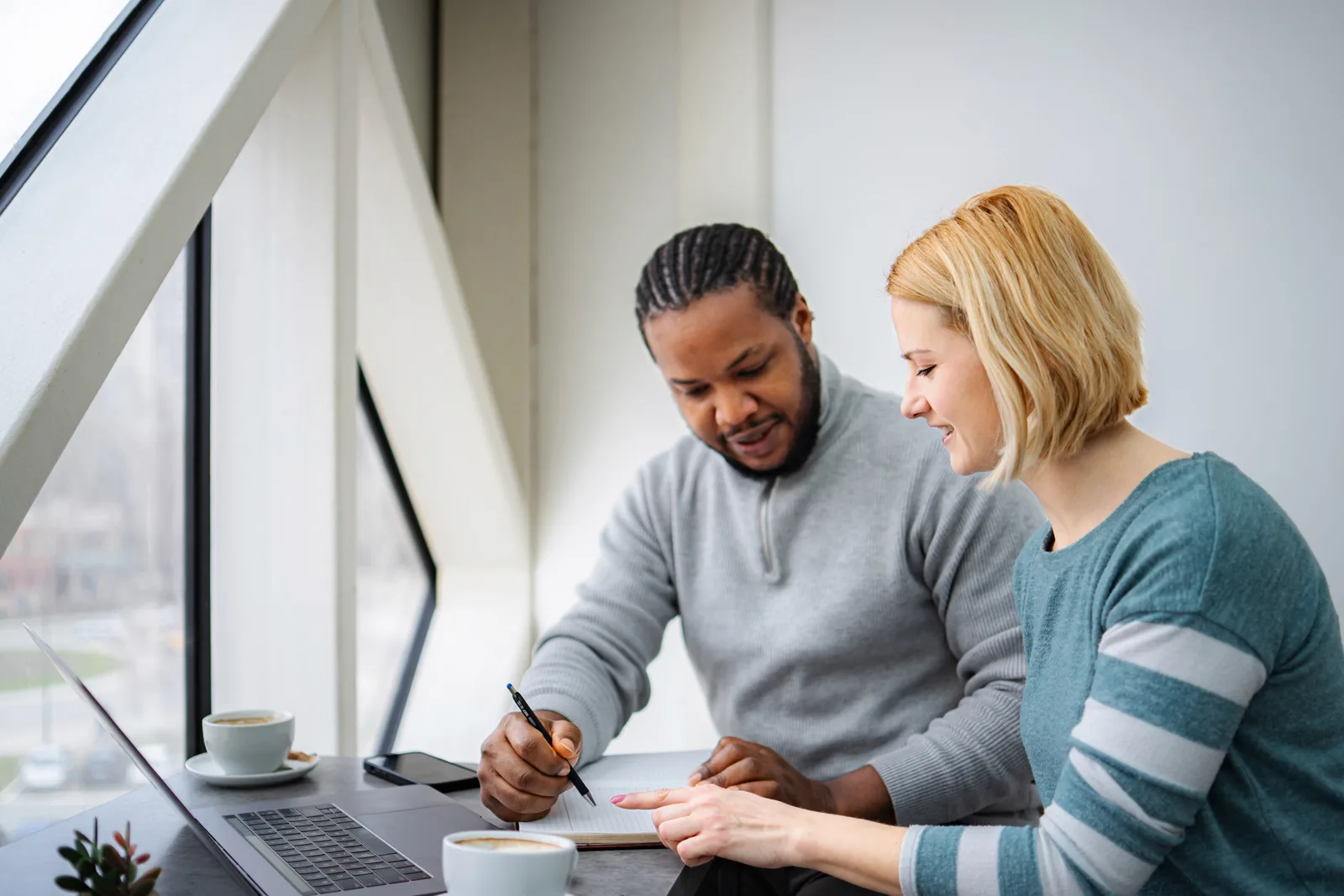 Two colleagues review a change list together on a laptop before pushing it out