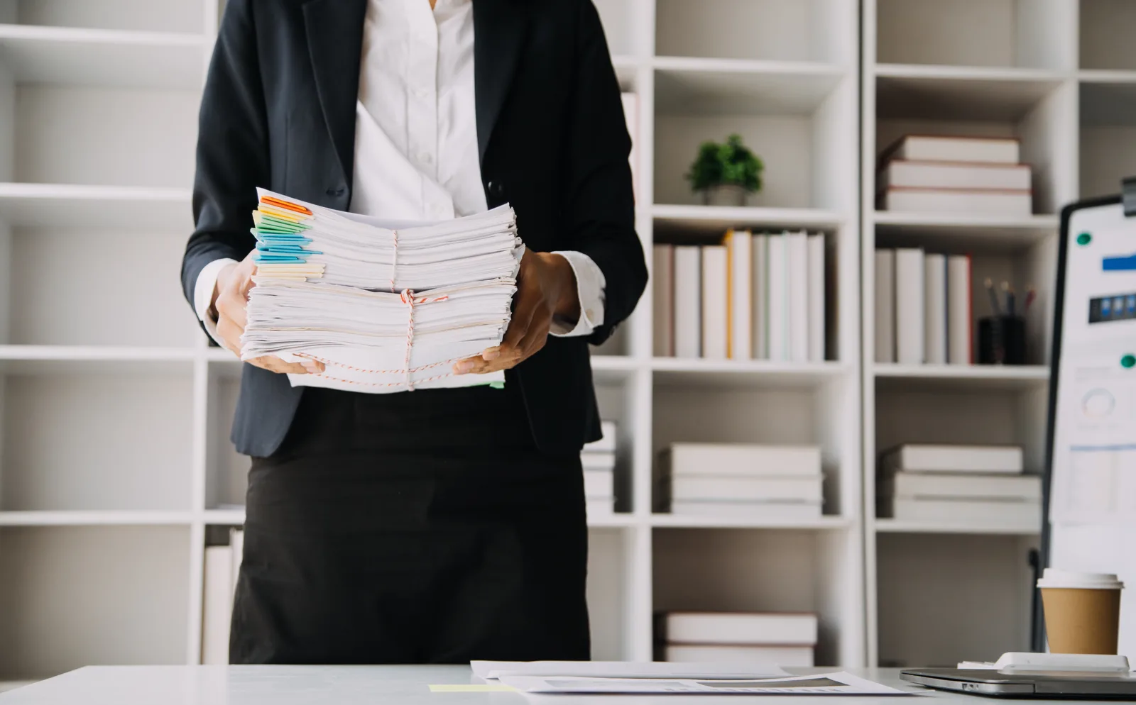 Hands sorting a stack of printed policy forms and certificates on an office desk