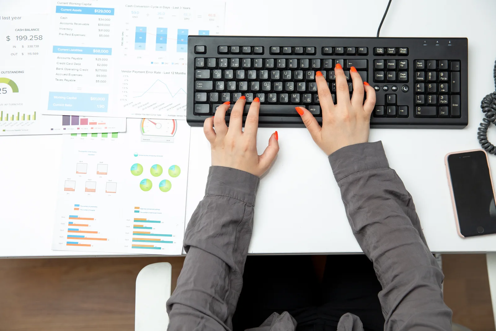 Staff member typing client policy details into a computer with an open paper folder beside the keyboard