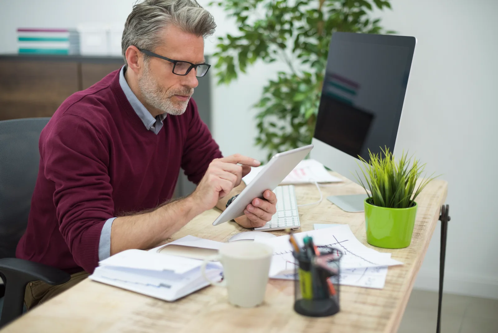 Small business owner checking payroll numbers on a printed spreadsheet with a calculator
