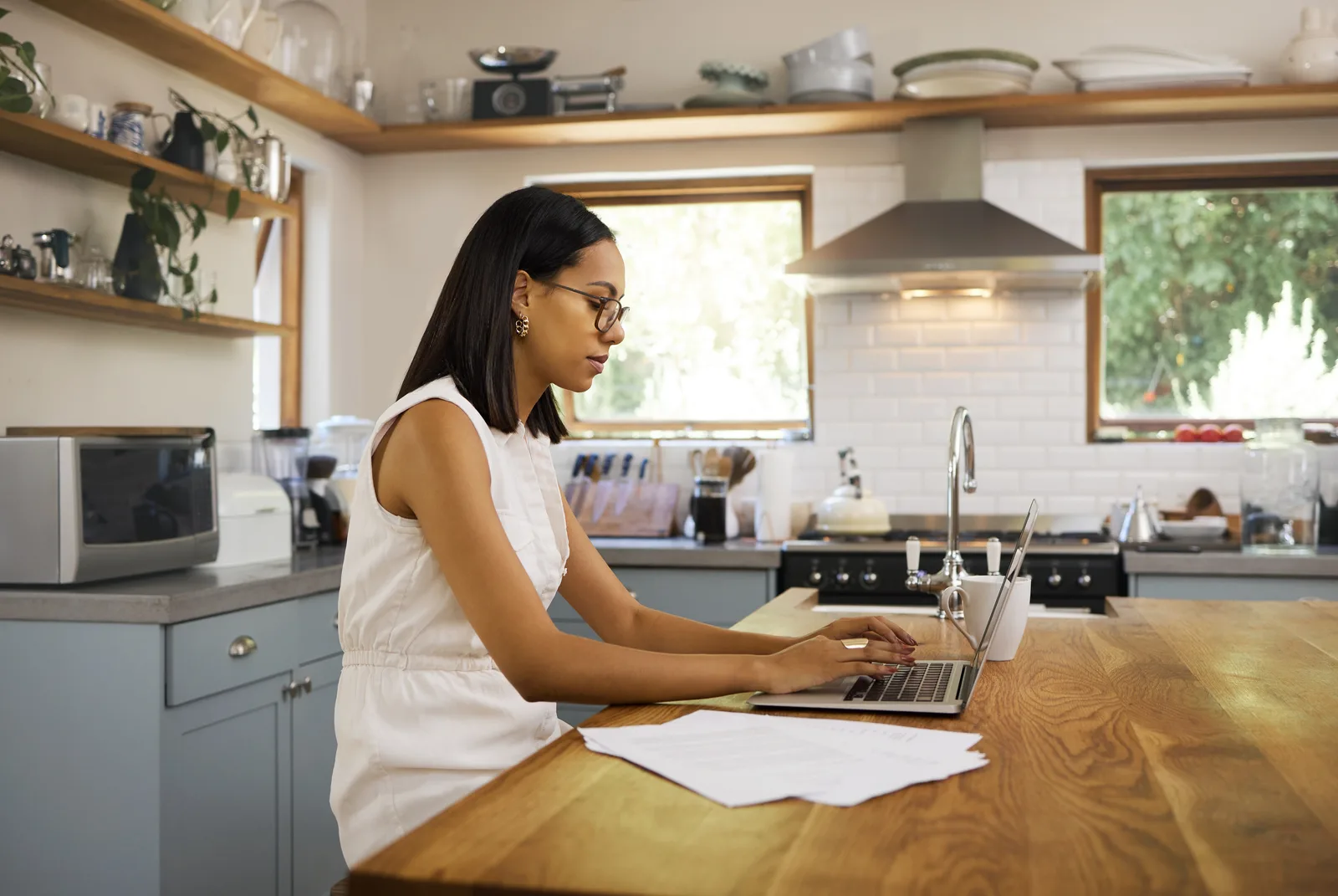 Freelancer at a kitchen table reading a contract on a laptop before signing