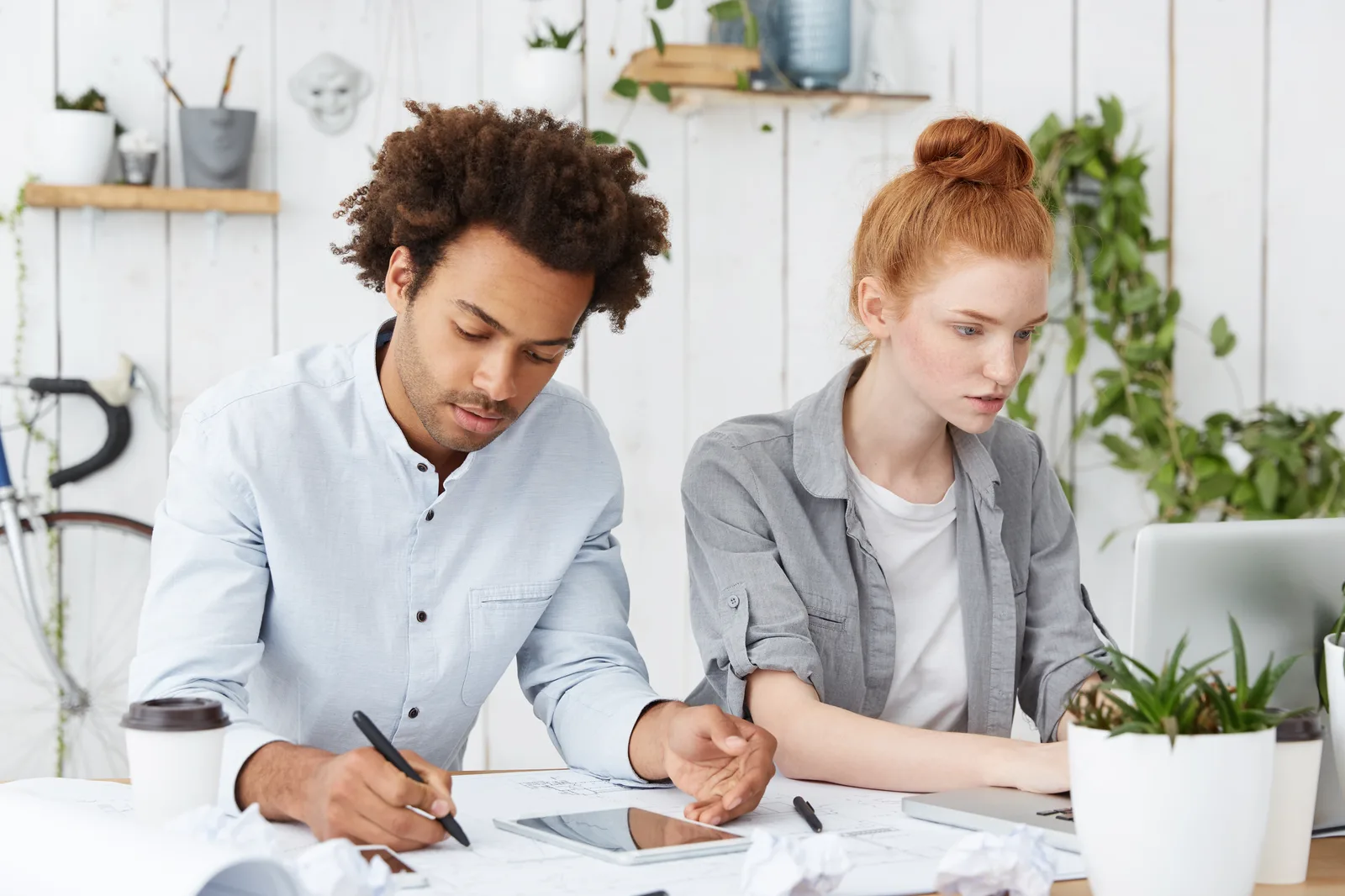 Two people going through tax forms and printed documents together at an office table