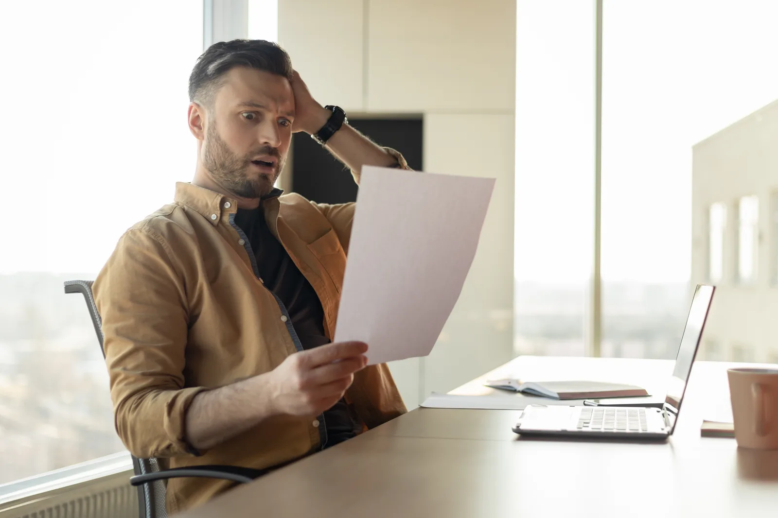 Business owner at a desk reading an official letter with a concerned look