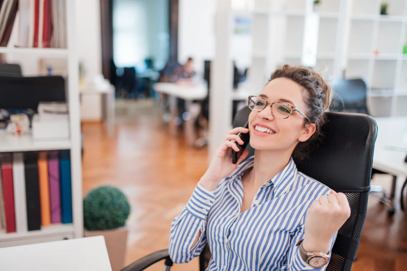 A business owner takes a call with a smile at her desk, the first fix of the week already working