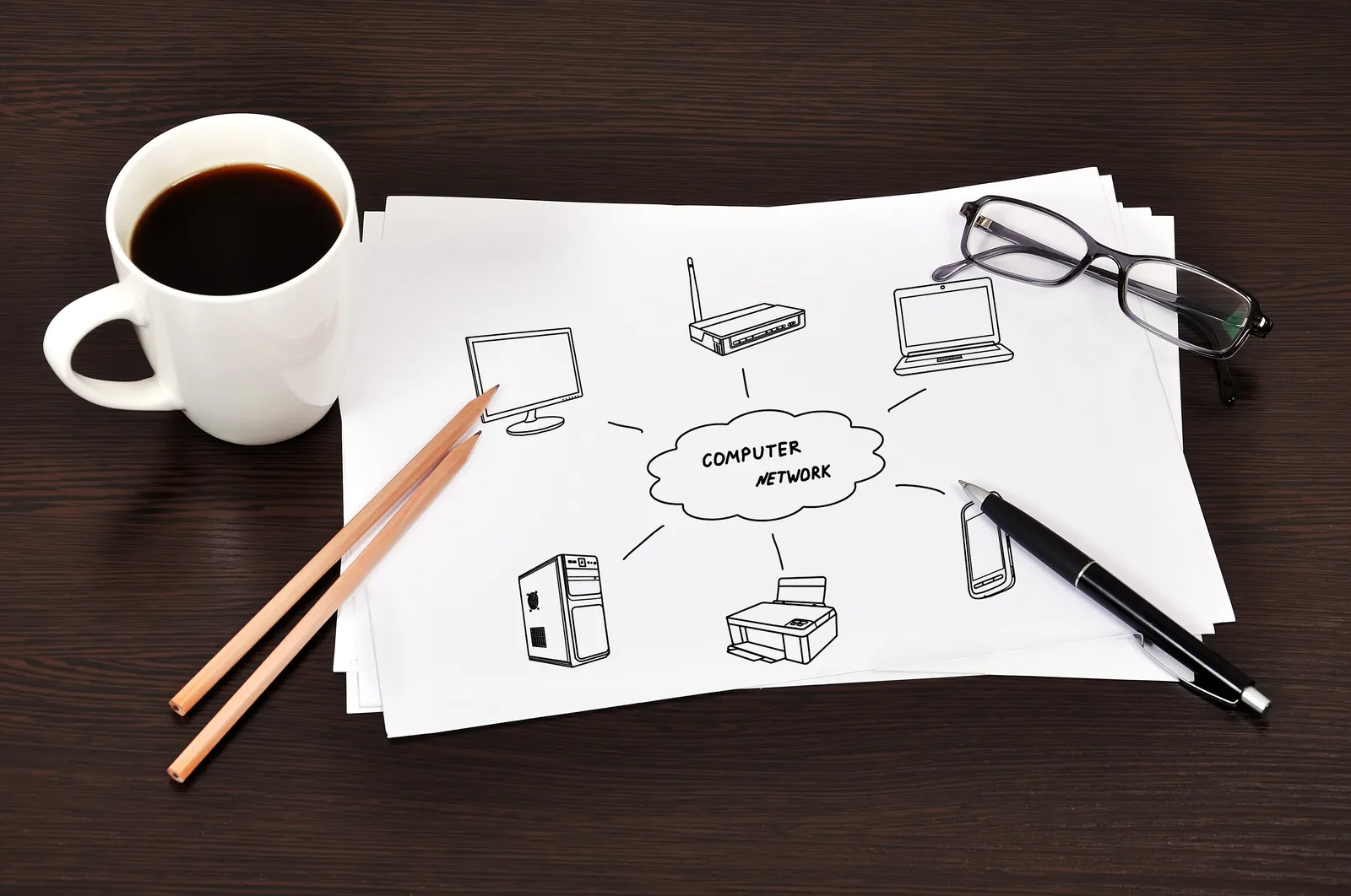 A sketched flow of connected devices on paper beside a coffee, glasses and a pen, the follow-up automation planned first