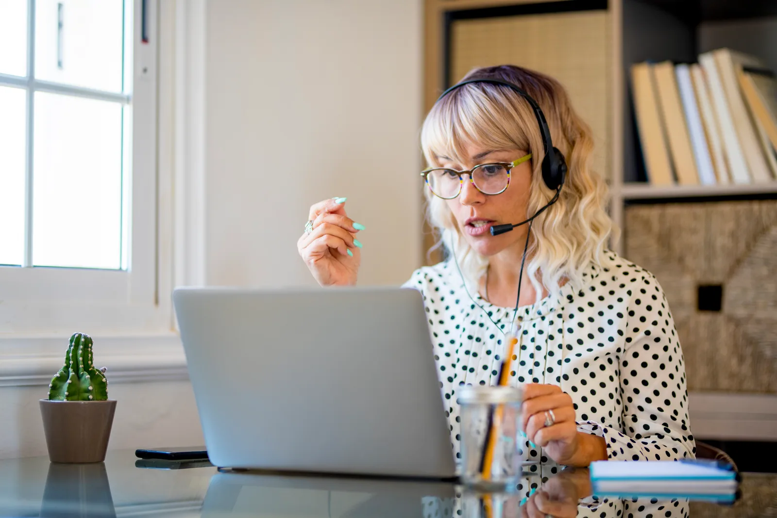 Remote support rep with a headset talks on a video call from a home desk